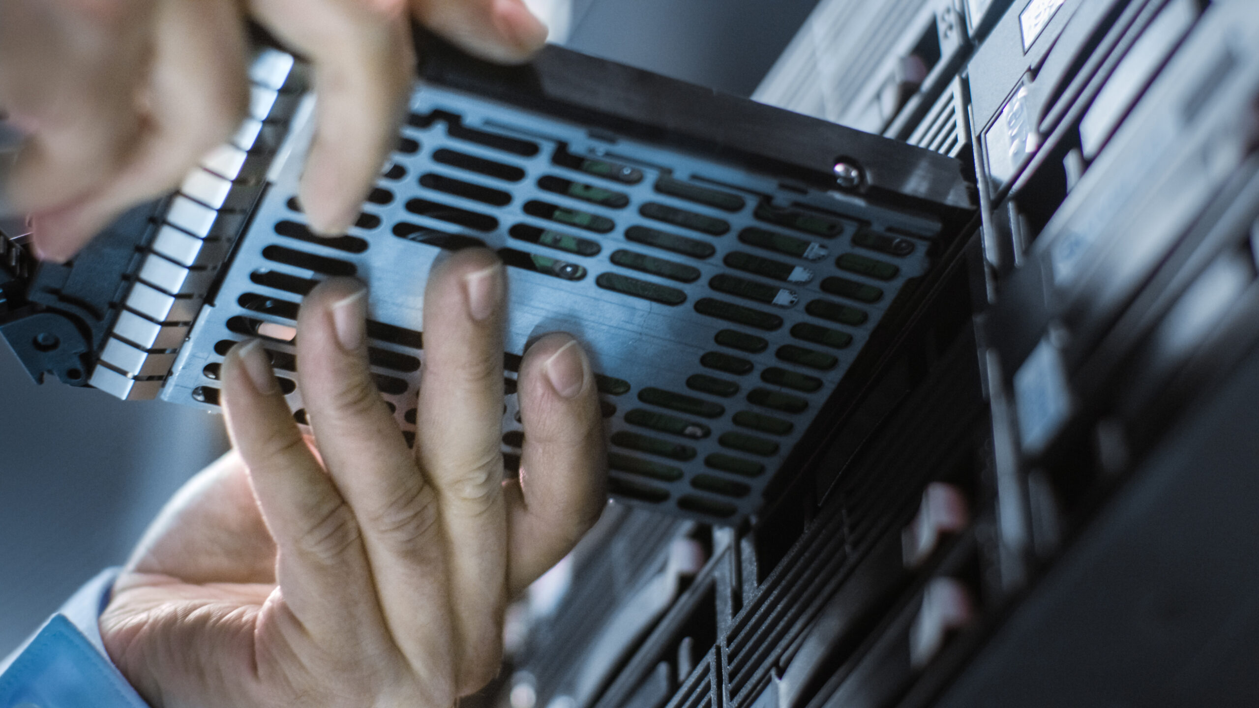 A person installs a data storage drive into a server, emphasizing the maintenance and configuration of IT infrastructure.